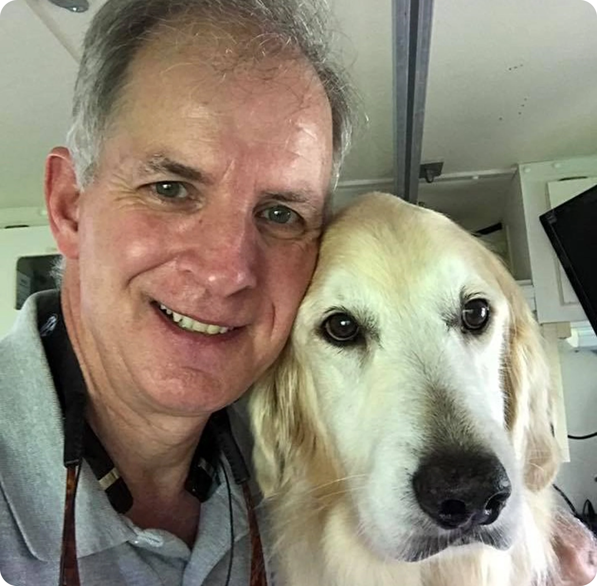 Man smiling with a golden retriever dog.