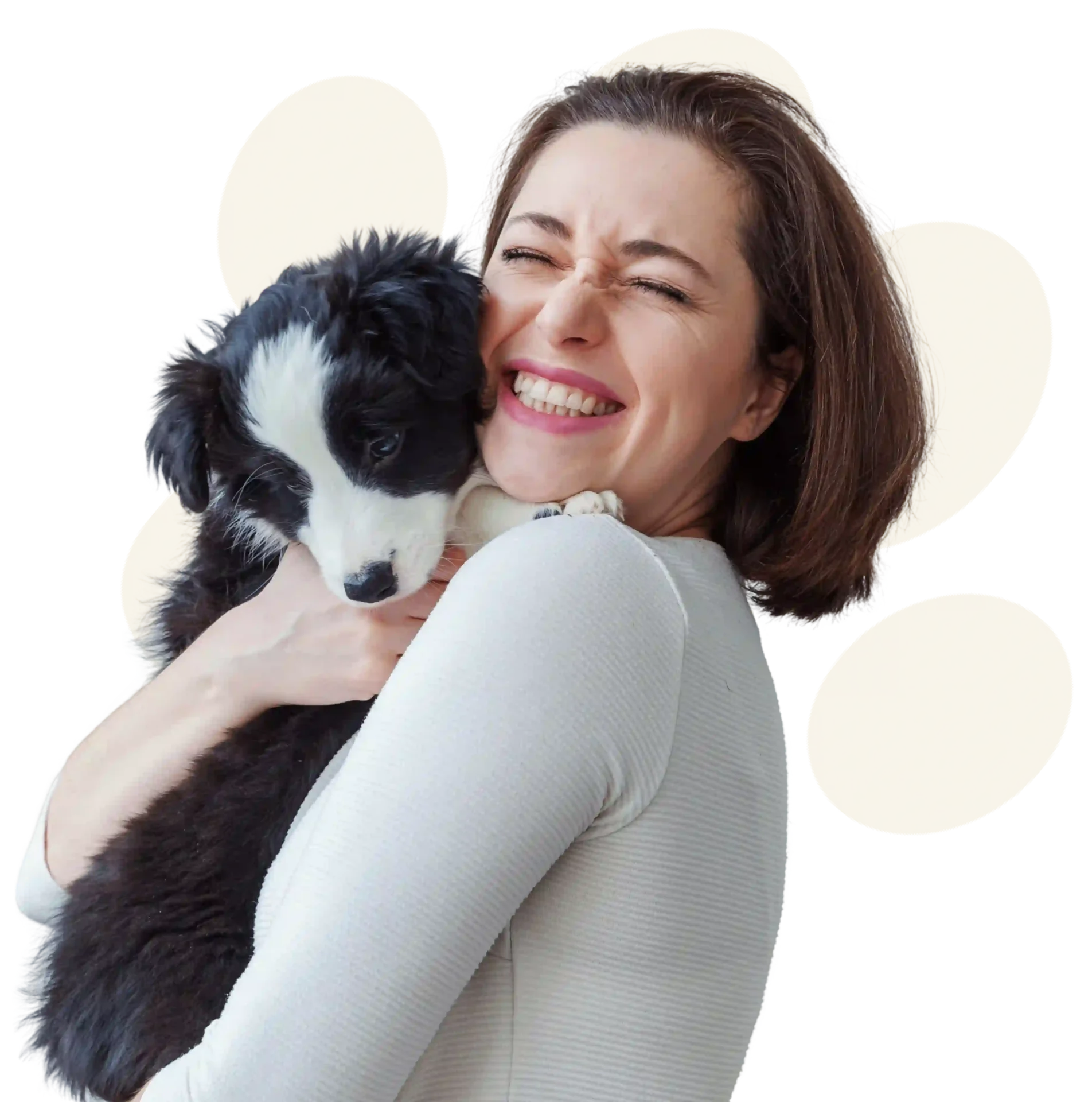 Woman joyfully hugging a black and white puppy.